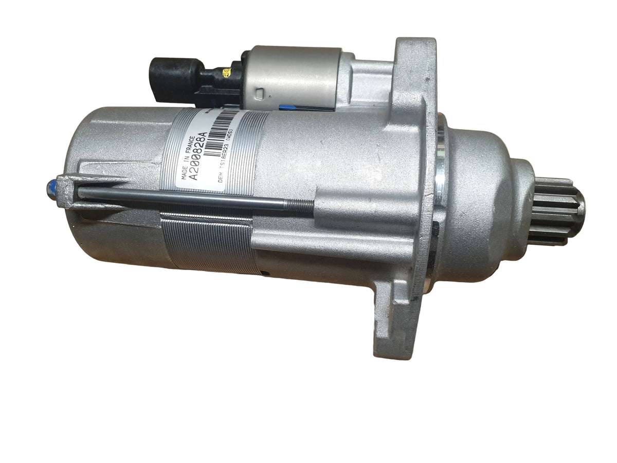 A New OEM automotive starter motor with a silver metal casing, black terminal connector, resting on a white background